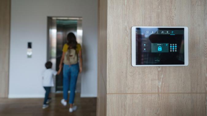 Latin American mother and son leaving the house and locking the door using an automated security system - focus on foreground.
