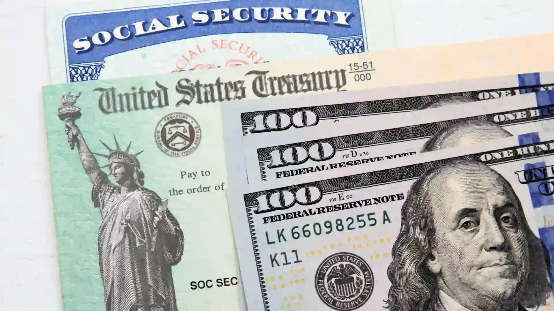 Partial view of Social Security card, US Treasury checks and hundred dollar bills.