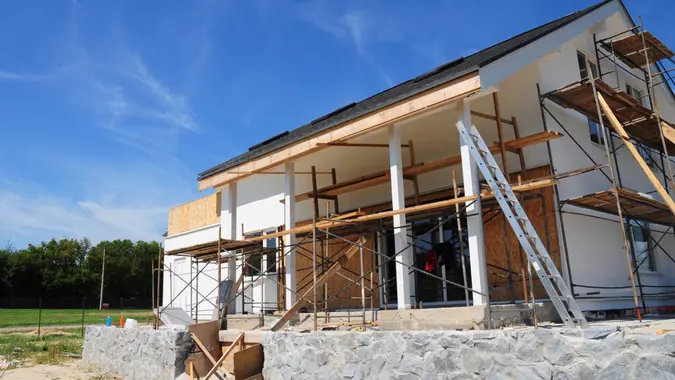 Renovate and repair residential house facade wall with mineral wool insulation, plastering, painting wall outdoors.