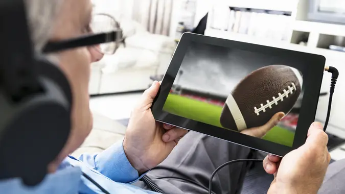 Man watching a football game on the tablet stock photo