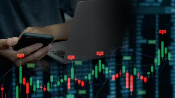 Businessman using mobile phone and computer to find financial information. Candlesticks and graphs of the stock market economy.Virtual screen business concept. stock photo