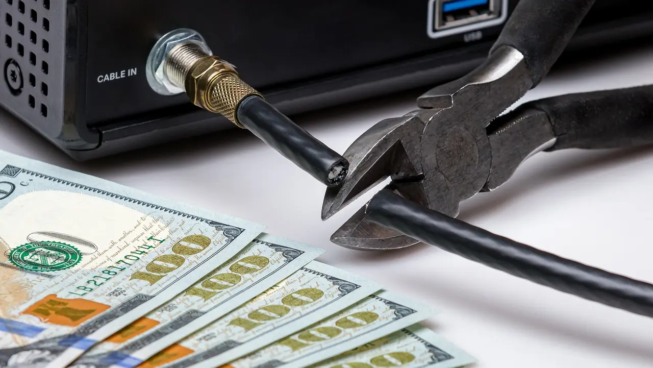 Cable TV cord being cut with cash money. Cord cutting, wireless, streaming television concept. stock photo