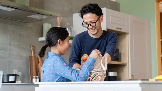Young girl helping her father to unpack groceries stock photo