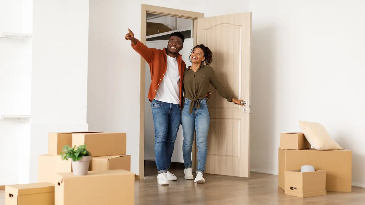 Excited black spouse entering new home, husband pointing aside Stock Photo