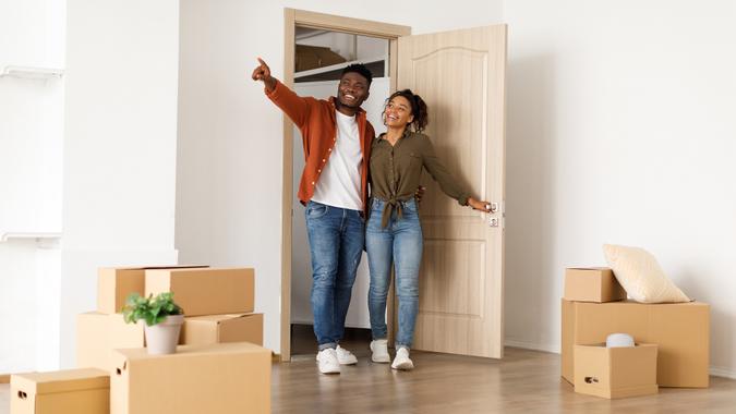 Excited Black Spouses Entering Their New Home, Husband Pointing Aside stock photo