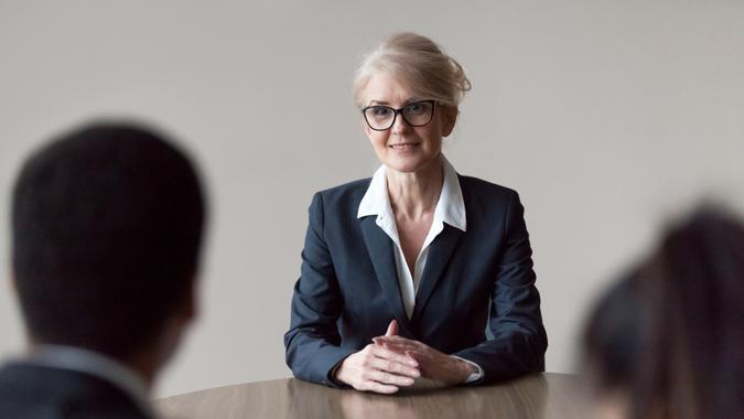 Smiling middle-aged female job applicant making first impression at interview Smiling middle aged senior female job applicant listening to hr questions making first impression at interview, recruiters interviewing older mature candidate, recruitment, age and employment concept.