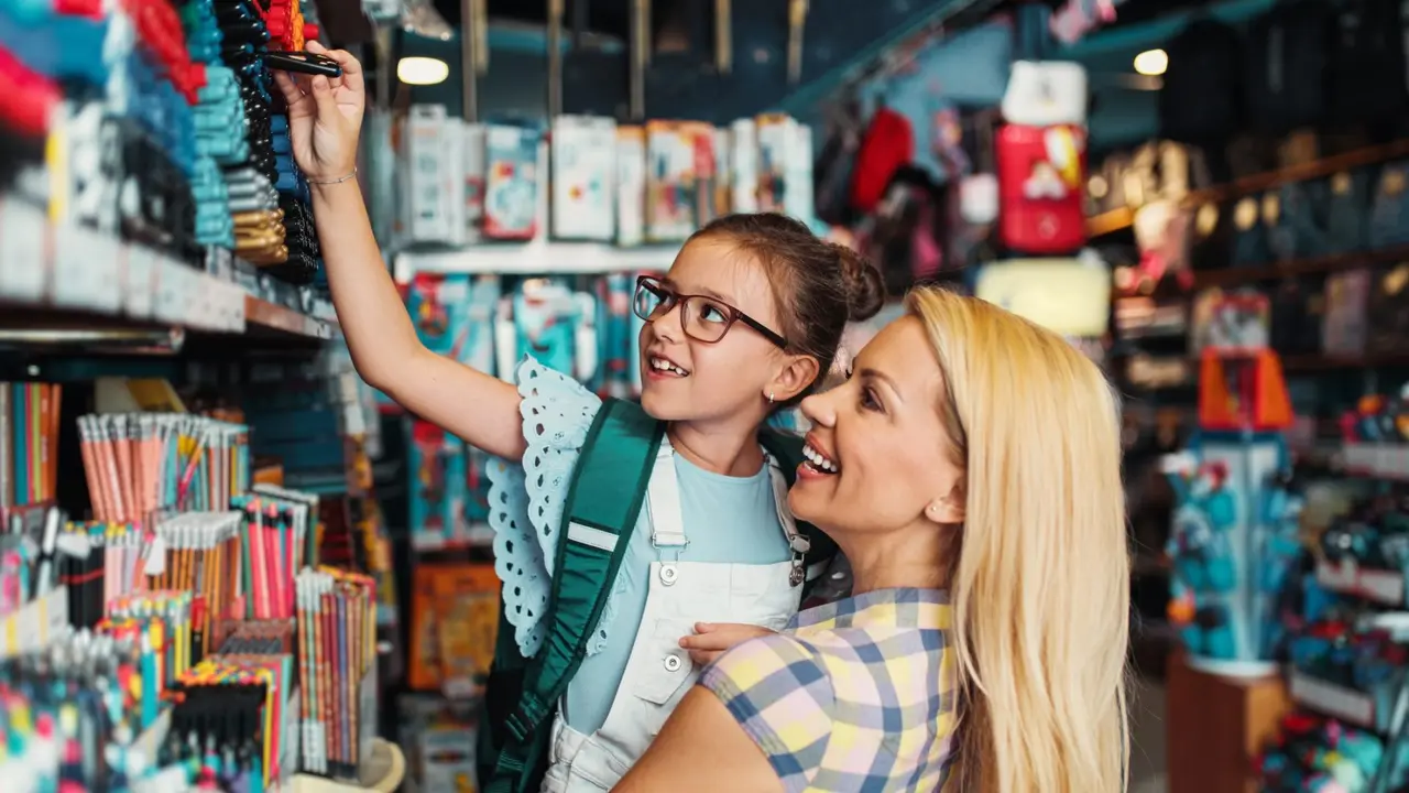 Happy mother with her daughter choosing and buying school supplies.