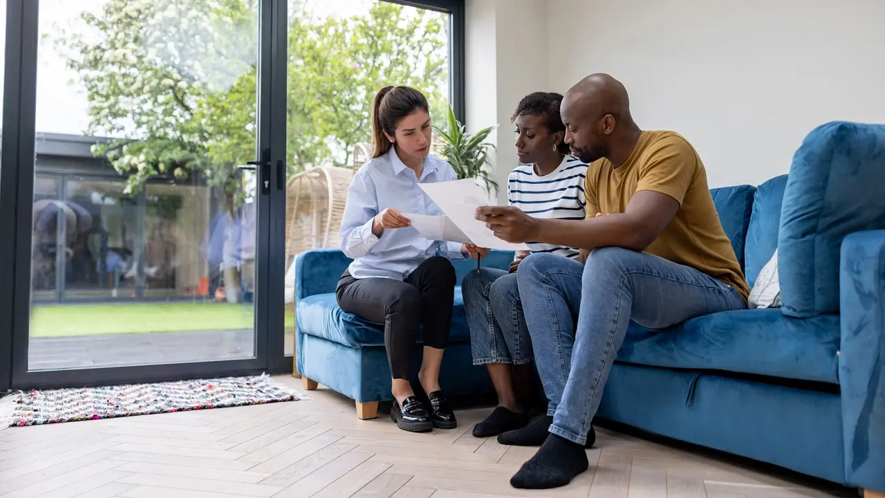 Couple buying a house and reviewing the contract with their real estate agent stock photo
