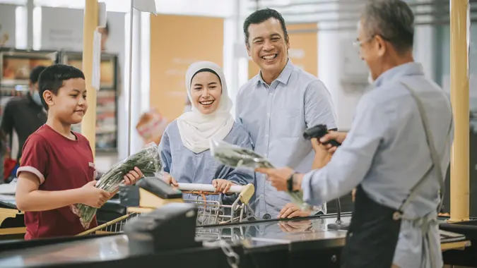 Asian malay family with one child check out at supermarket cashier buying dairy product and vegetables stock photo