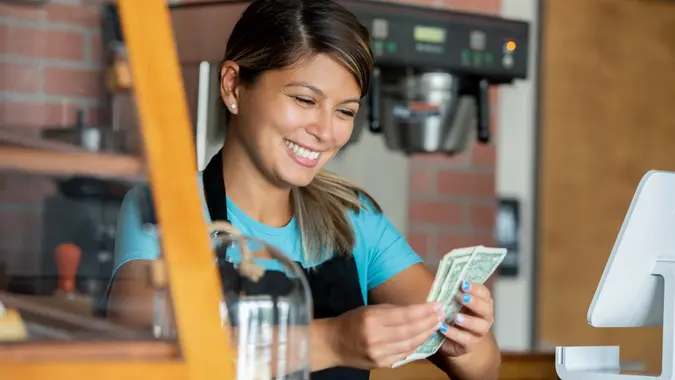 Barista counting her tips after working shift at local coffee shop stock photo