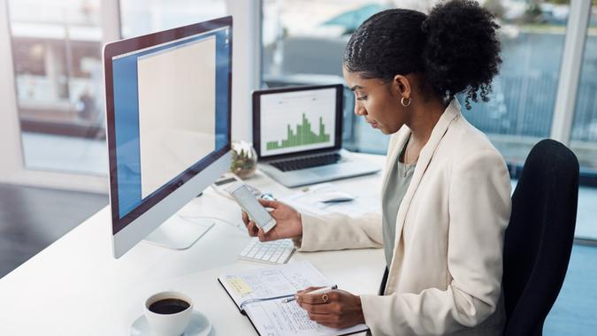 Shot of a young businesswoman using a mobile phone at her desk in a modern office.