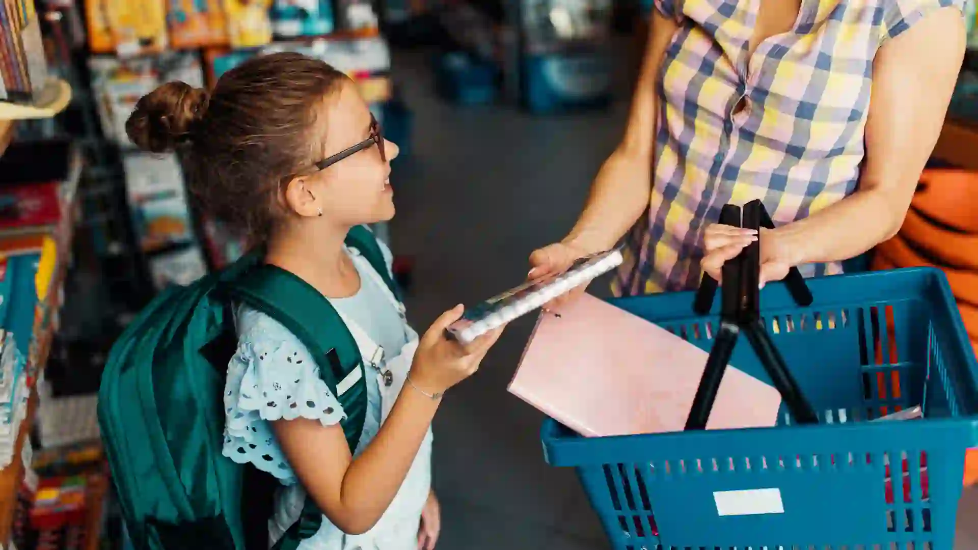 Happy mother with her daughter choosing and buying school supplies.