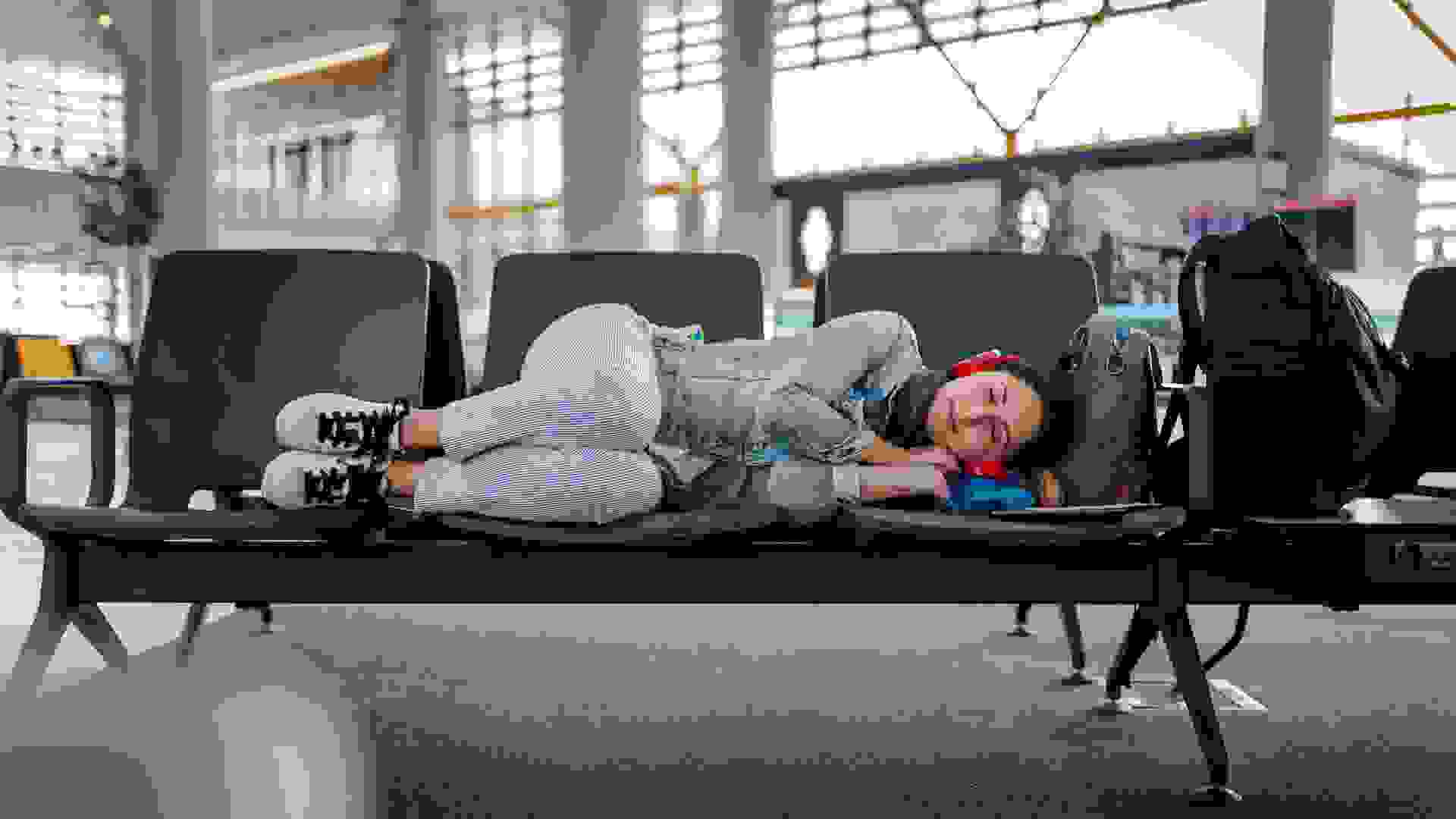 Young Woman waiting for delayed flight and sleeping on chairs.