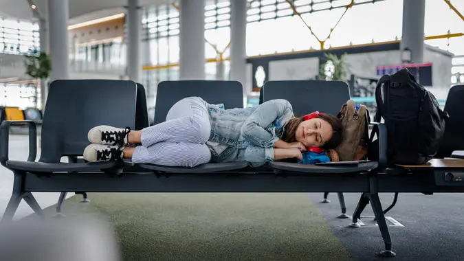 Young Woman waiting for delayed flight and sleeping on chairs.