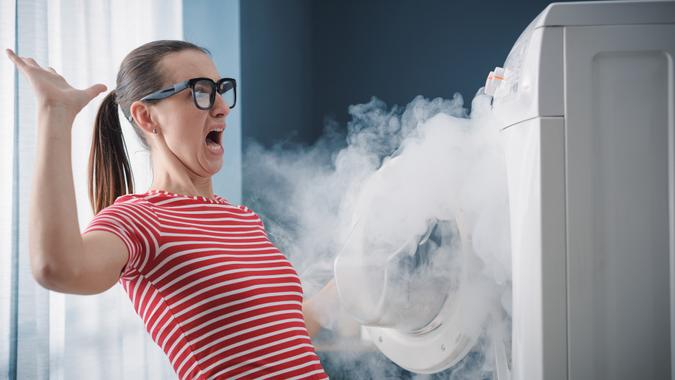 Scared woman dealing with a broken burning appliance at home.