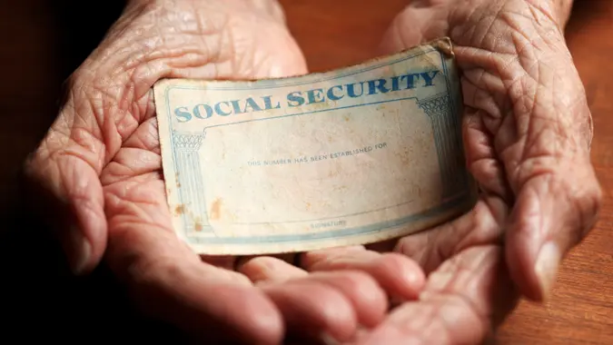 Close up of Aging female hands holding Social Security card.