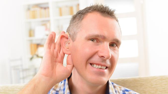 Man showing deaf aid in ear.