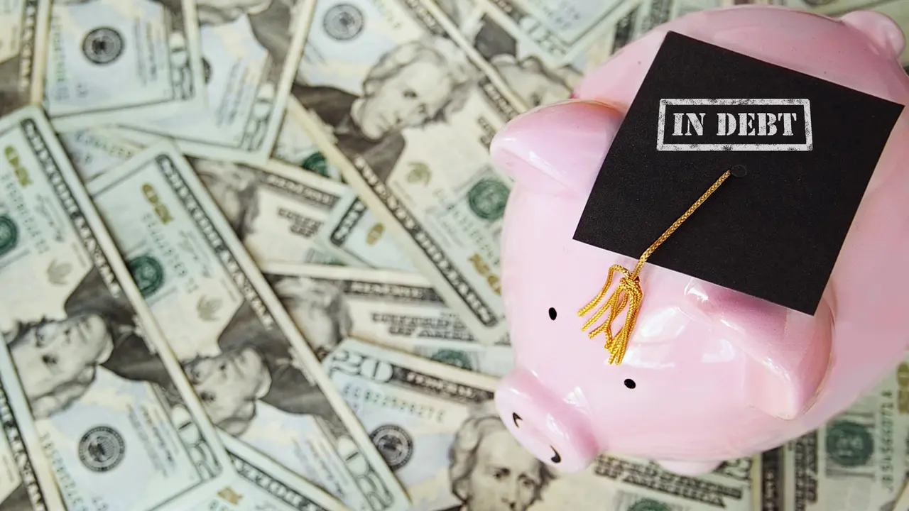 A piggy bank with a graduation cap on that says in debt -- with a background of cash.