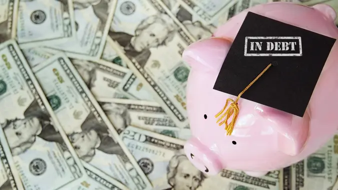 piggy with In Debt graduation cap on money.