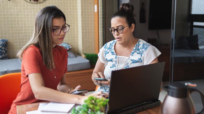 Mother and daughter doing finances together at home stock photo