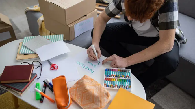 Redhead teenage boy writing on the paper" Donation" and "School supplies" stock photo