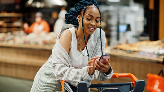 African american woman with shopping cart trolley in the supermarket store. stock photo