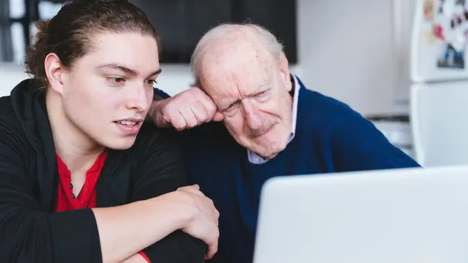 Son teaching his father how to invest online stock photo