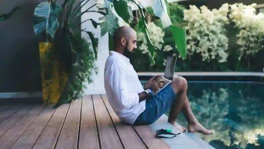 Side view of skilled businessman using laptop device for making online ticketing and banking during resort recreation on Bali island, Middle Eastern digital nomad connecting to villa wifi on netbook.