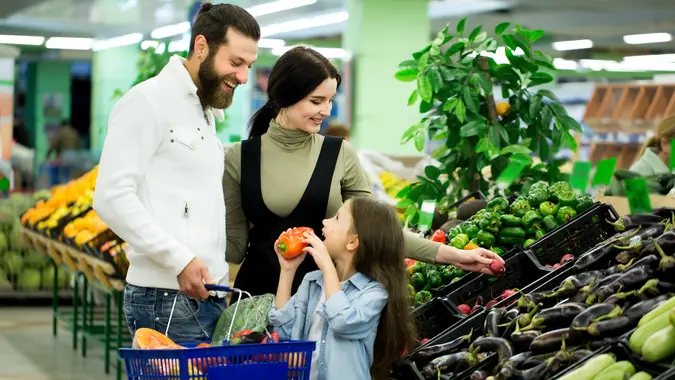 A woman with a man and a child, choosing vegetables while shopping in a vegetable supermarket. stock photo