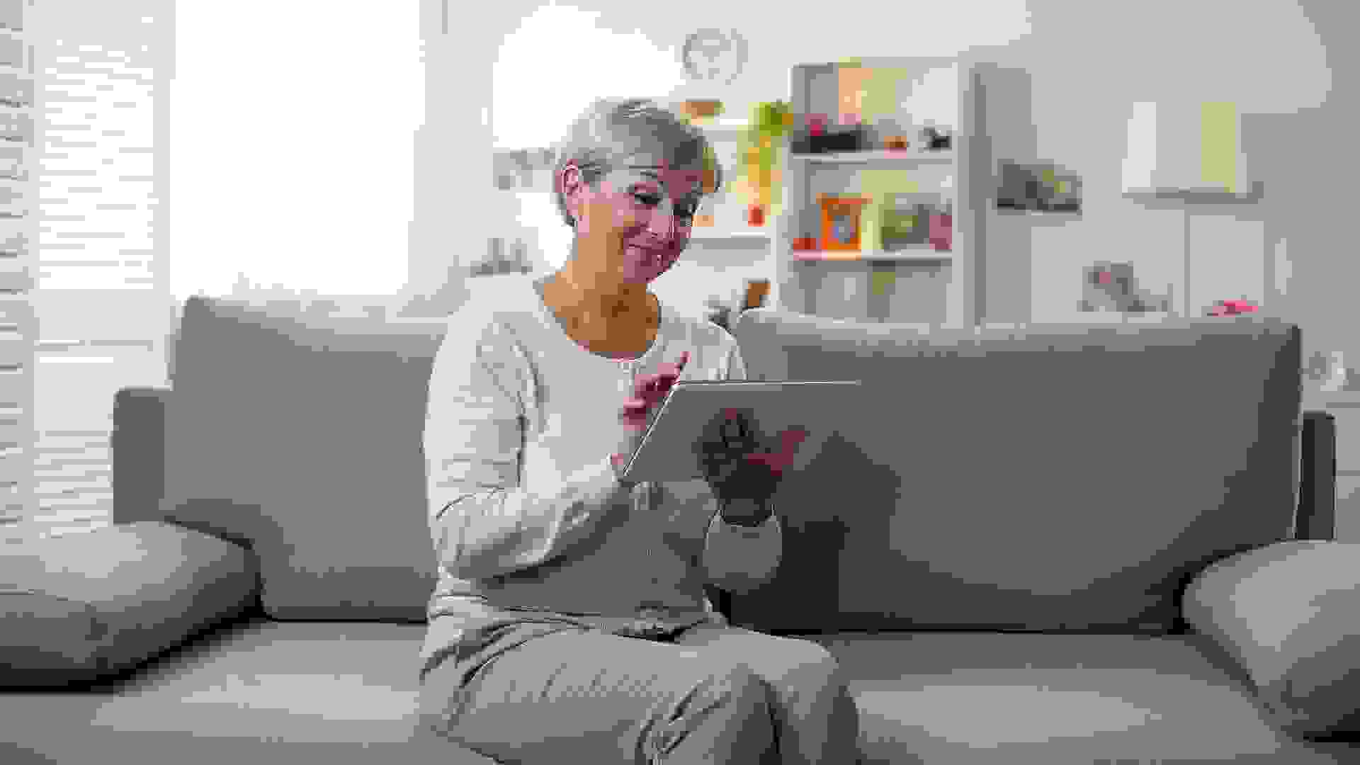 Happy aged woman watching photos on tablet and smiling, spending free time.