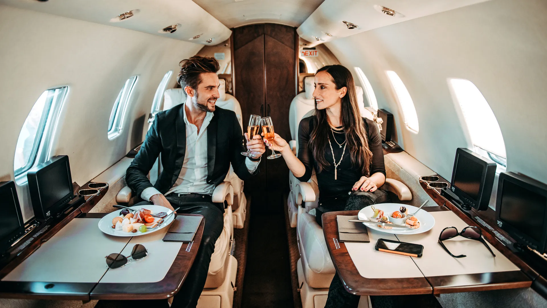 A rich couple makes a toast while sitting in their private jet.