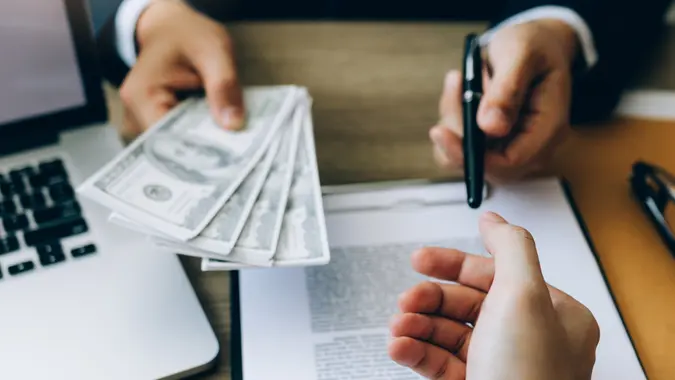 Partner has made a fraud in the contract of sale and being handed a cash and pen to the businessman signing the contract corruption bribery concept.