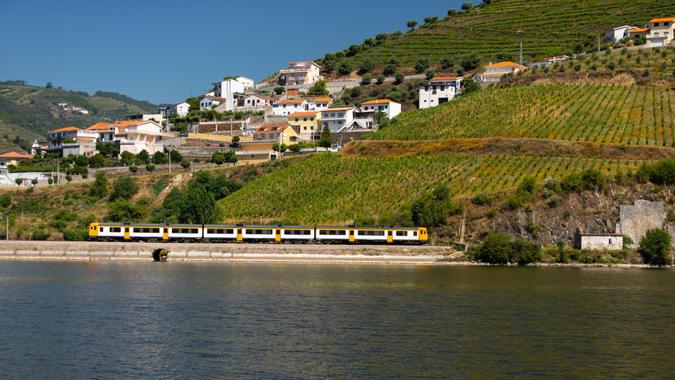 Yellow train passing in Douro railway and vineyards as background.