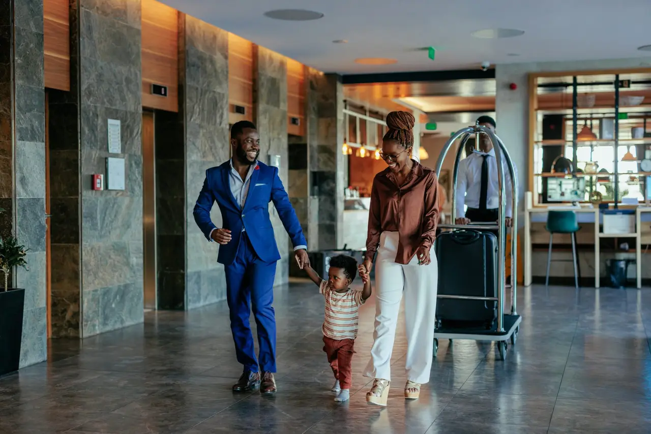 An African American family is walking through the lobby of a luxurious resort.
