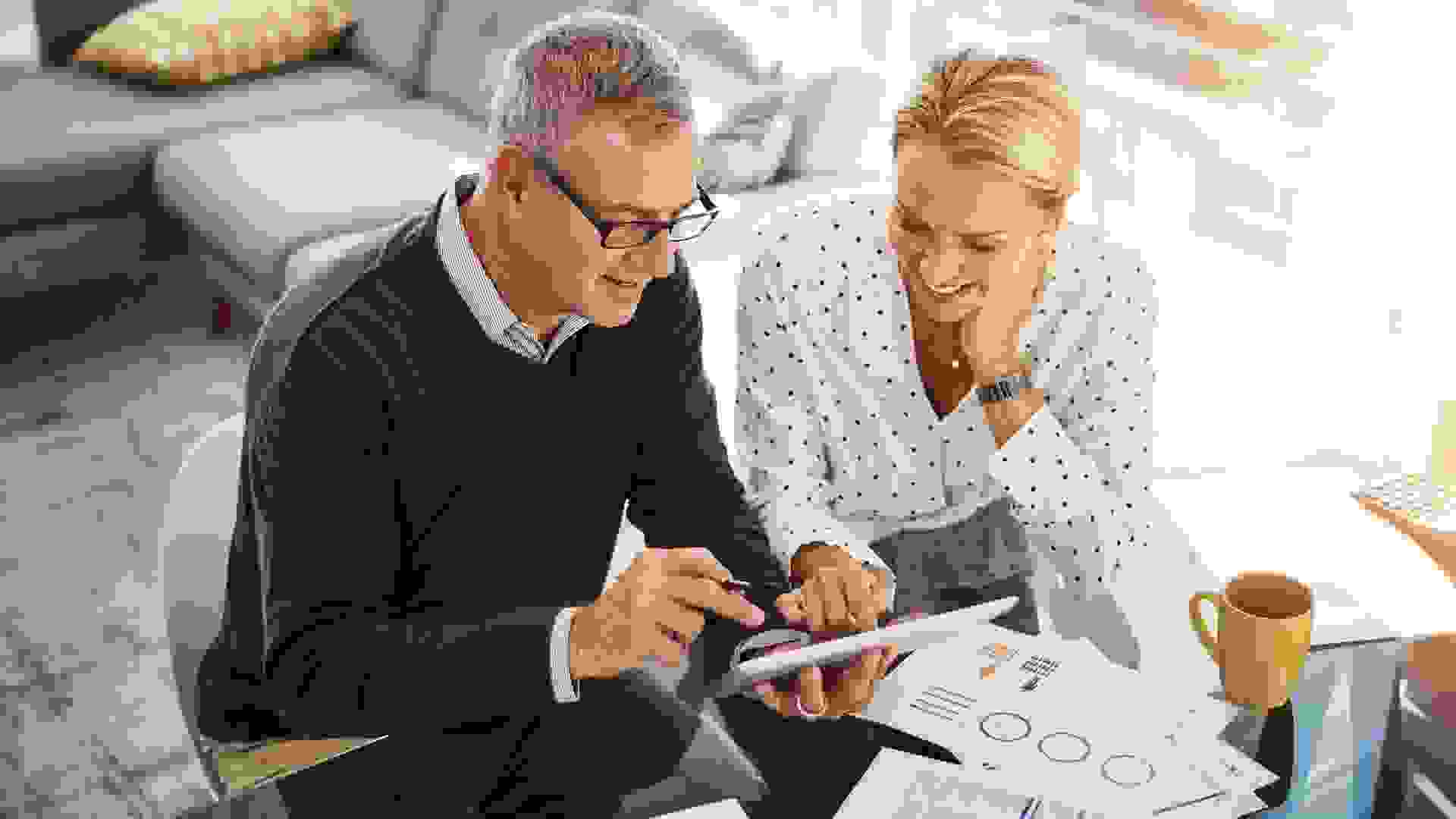 Shot of a mature couple using a digital tablet while going through paperwork at home.