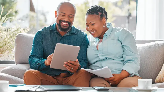 Shot of a mature couple looking through their bills while using a digital tablet stock photo
