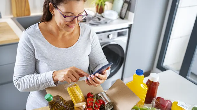 Woman unpack and check list of groceries received from supermarket stock photo