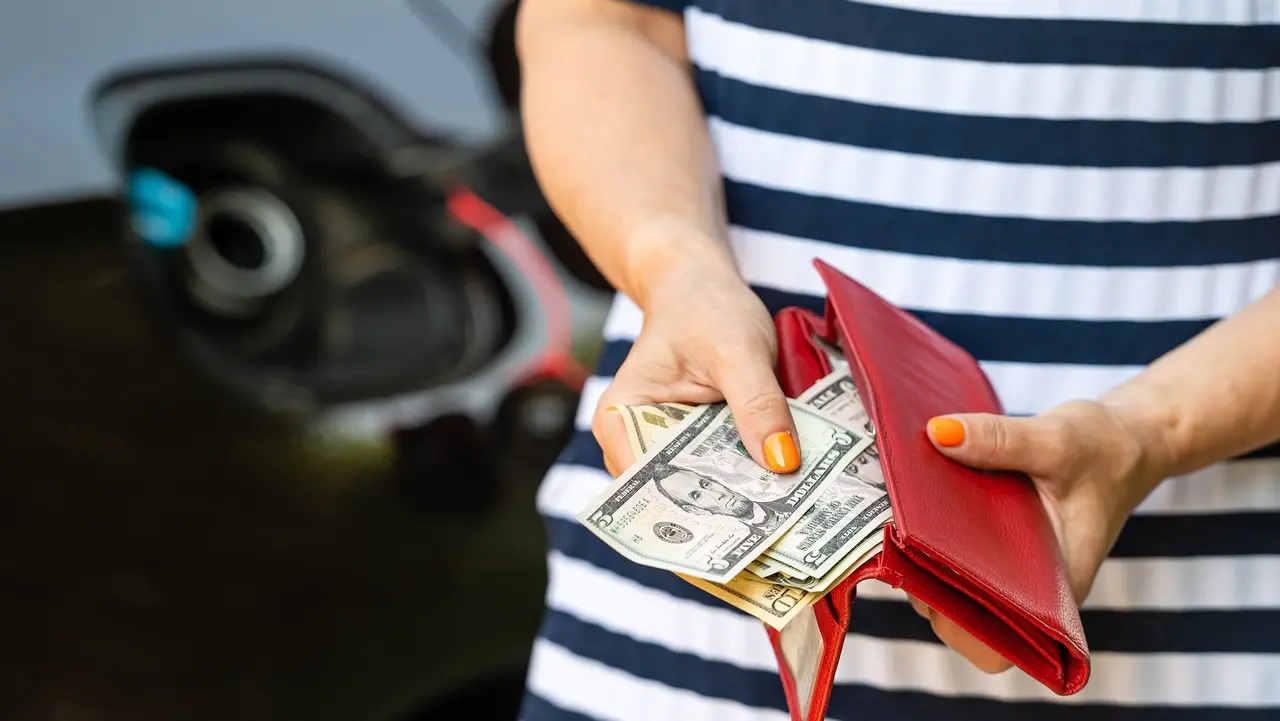 A woman counts money standing at an open fuel tank, the concept of rising fuel prices, closeup stock photo