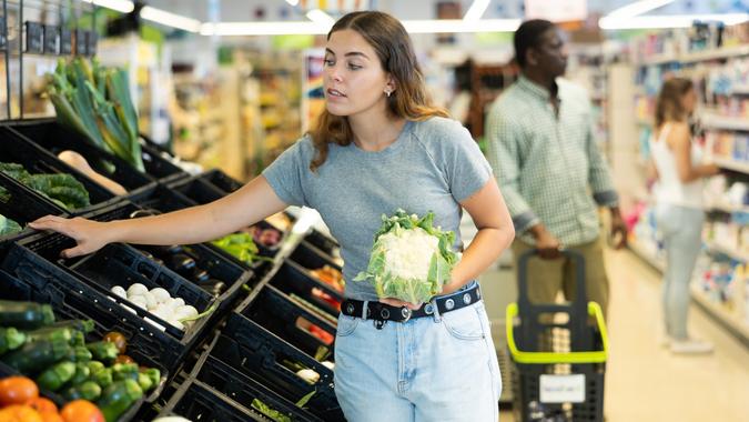 Portrait of woman buying fresh cauliflower in grocery shop stock photo