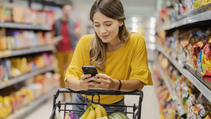 Purchasing Goods with Smartphone at Grocery Store stock photo