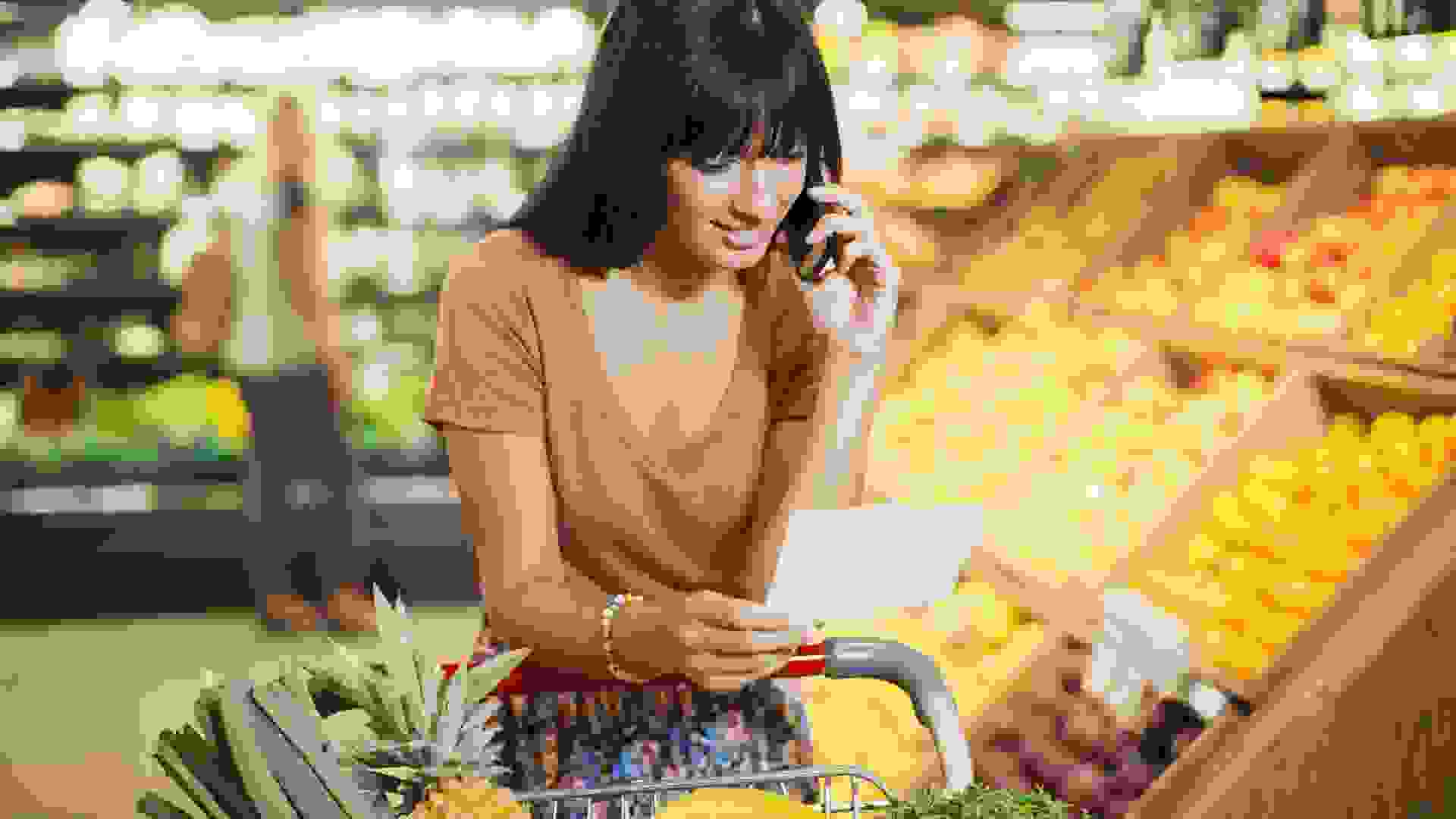Woman talking on cell phone and shopping in grocery store stock photo