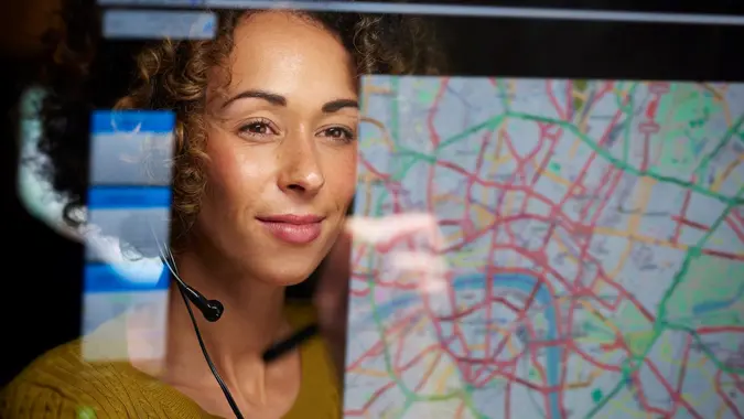 a female logistics worker is organising dispatch of freight on her interactive digital map whilst talking on her headset.