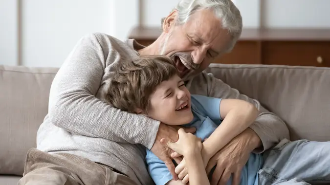 Overjoyed senior grandfather play with small grandson stock photo