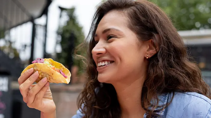 Happy woman eating tacos at a restaurant stock photo