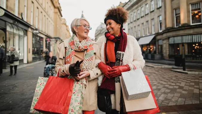 Two female adult friends walking through the city streets at Christmas.