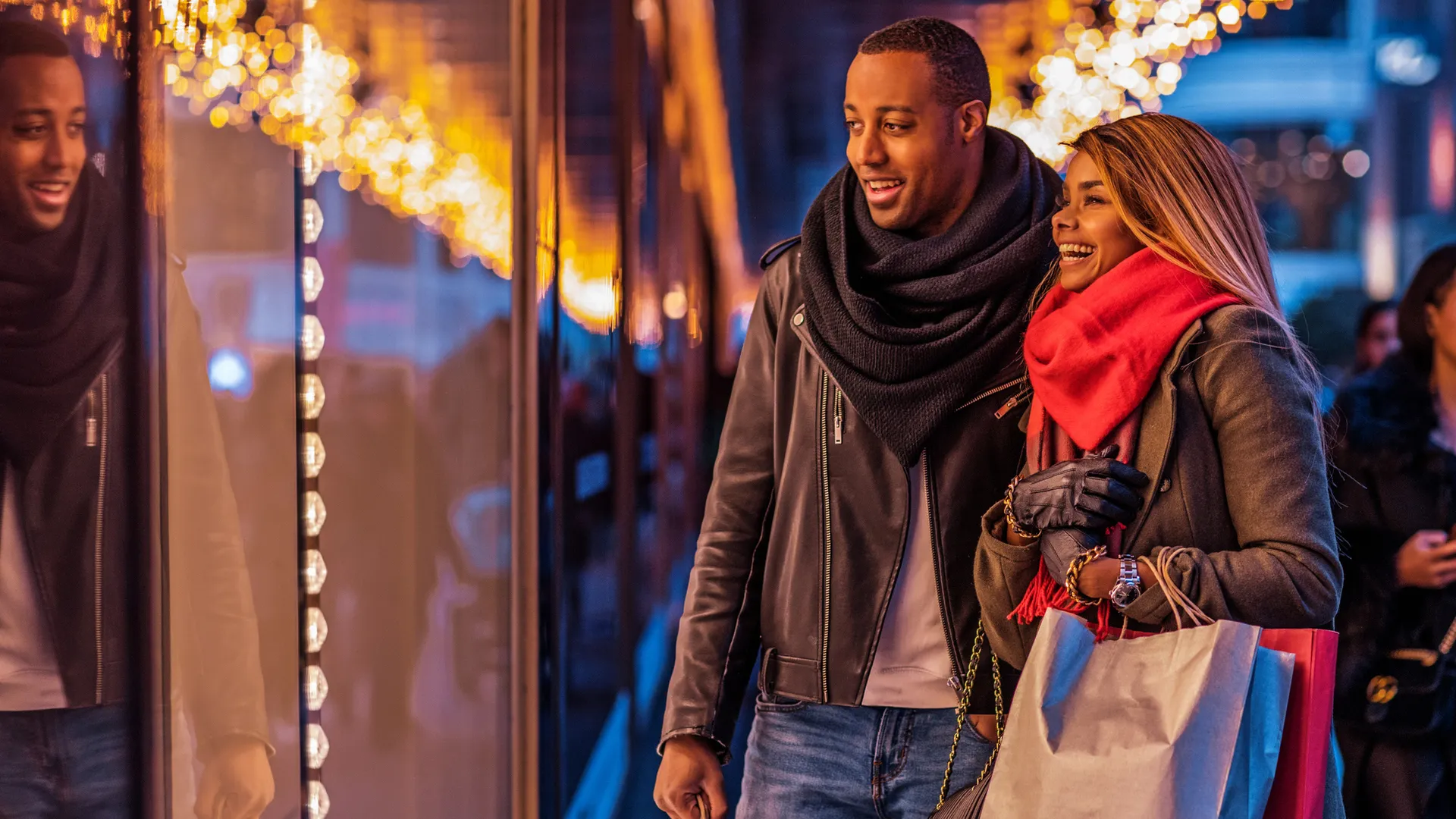 Beautiful black male and female couple enjoying winter shopping in the high street.