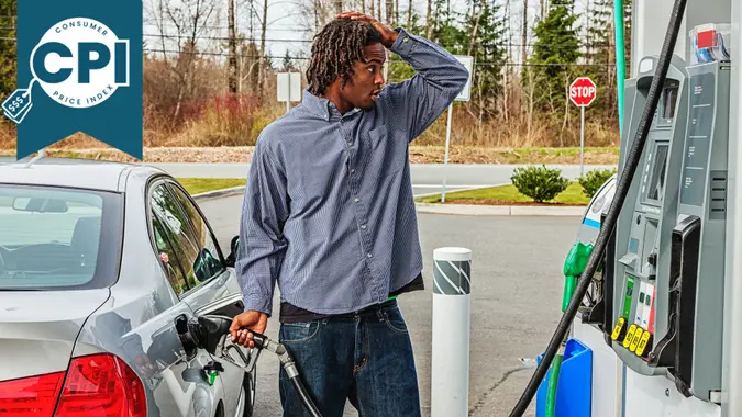 Photo of a young African American man at a gas station, filling his tank with a look of shock as he looks at the sale price.