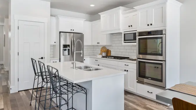 Stainless steel double oven and french door refrigerator add contrast to white kitchen.
