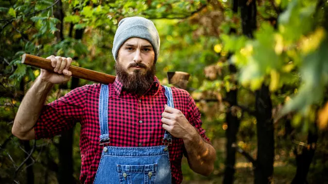 Lumberjack, attractive looking - A lumberjack in the forest works on a daily basis to prepare and cut wood - Muscular lumberjack.