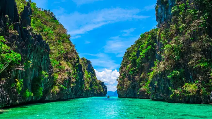 Tropical landscape with rock islands, lonely boat and crystal clear water, El Nido, Palawan, Philippines.